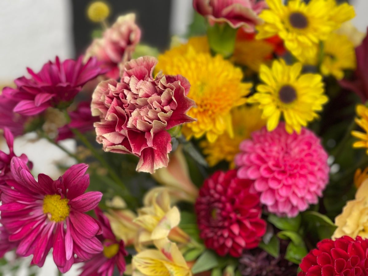 a vase filled with lots of different colored flowers