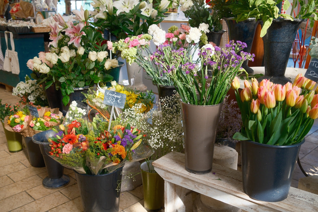 Assortment of colorful flowers in buckets and vases.